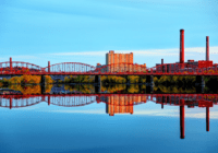 Landscape image of a red bridge over water near a city in Massachusetts.